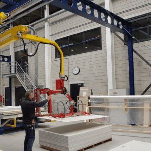 man using a vacuum lifter to load wood panels onto a pallet